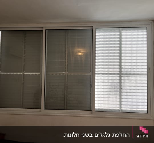 תריסים סגורים על חלון גדול עם מסגרת לבנה